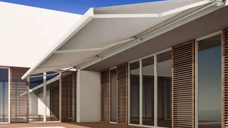 Store banne coffre Design 440 à toile blanche déployé au-dessus d’une terrasse en bois