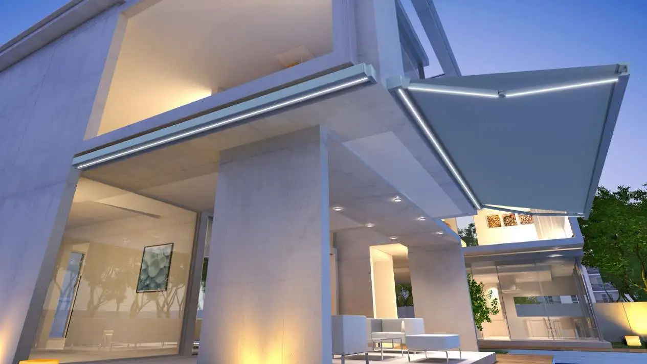 Store banne coffre Karré 430 à bras LED déployé devant une maison contemporaine éclairée de nuit