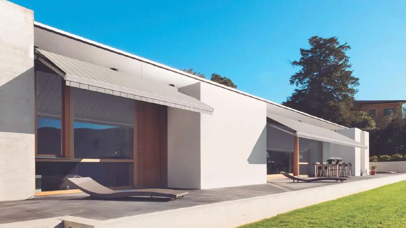 Store banne loggia Design 210 déployé au-dessus de la terrasse d’une maison blanche contemporaine