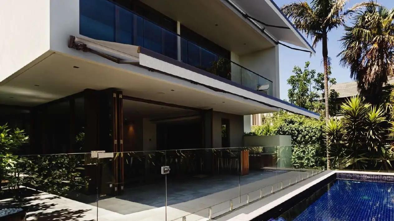 Store banne monobloc Select 100 déployé au-dessus de la terrasse d’une maison contemporaine avec piscine